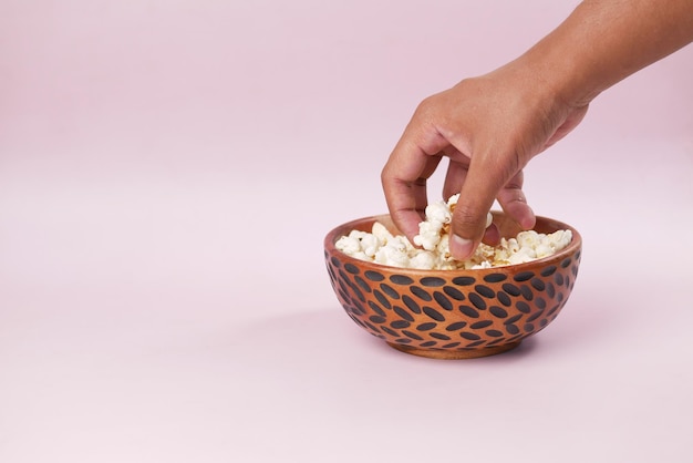 Young man picking popcorn from a bowl with copy space