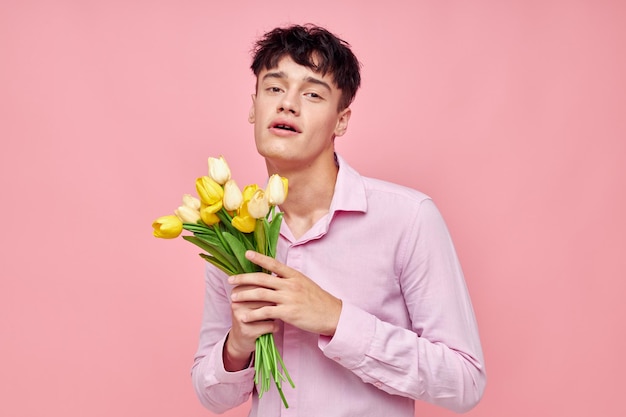A young man in a pink shirt with a bouquet of flowers gesturing with his hands isolated background unaltered