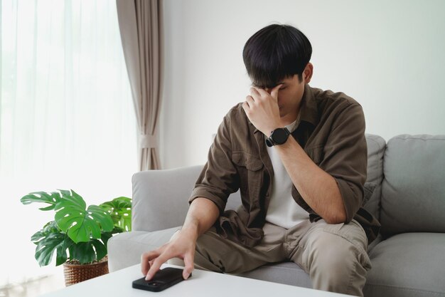 The young man placed his phone on the table and was sitting on the sofa in the living room