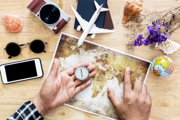 Young man planning travel on vacation trip with map. Top view.