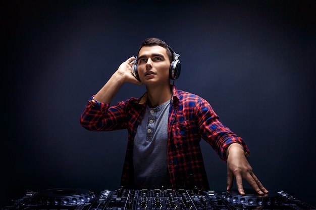 Young man play music on a dj&#39;s mixer at studio