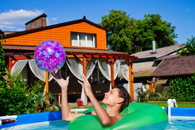 Giovane che gioca a giochi attivi in piscina lanciando una palla gonfiabile divertimento e intrattenimento estivo ...