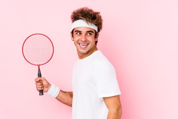 Young man playing badminton isolated looks aside smiling, cheerful and pleasant.