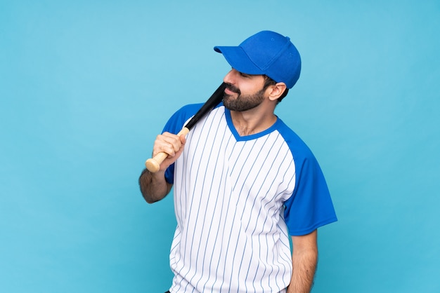 Young man playing baseball over isolated blue background laughing