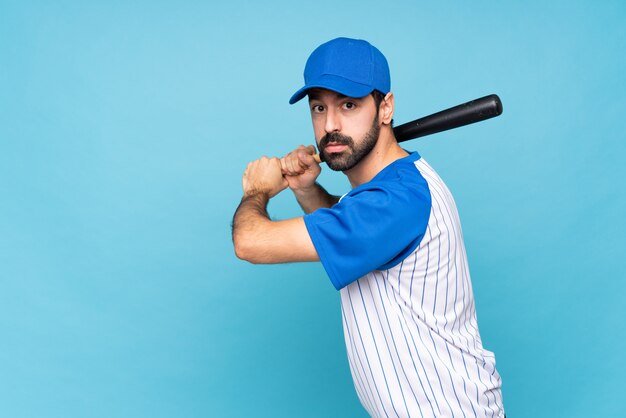 Young man playing baseball over isolated blue wall