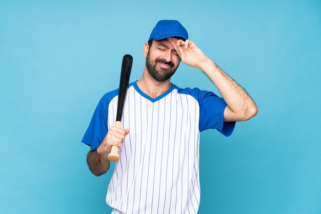 Young man playing baseball over isolated blue with tired and sick expression