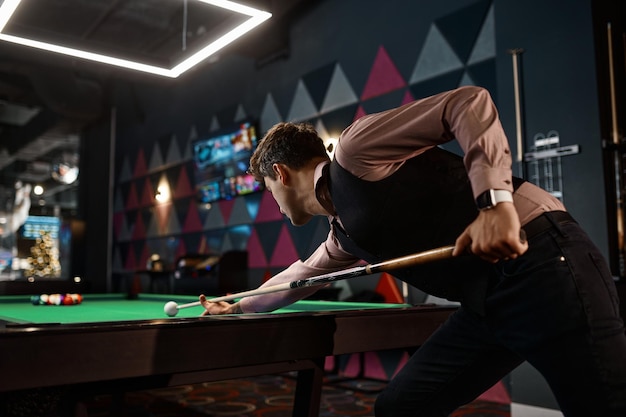 Young man playing billiard at night club