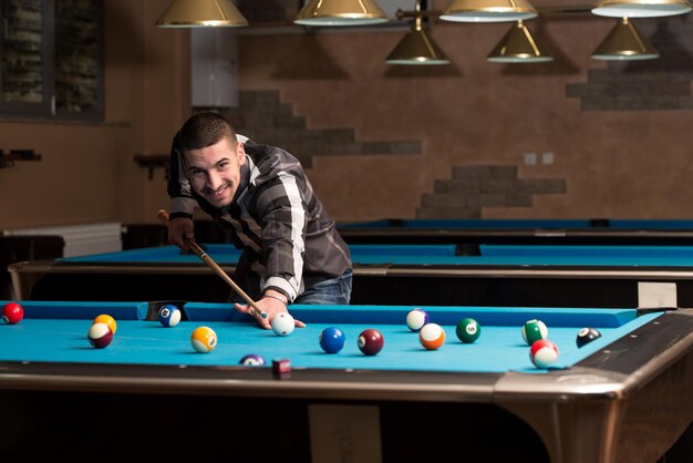 Young Man Playing Billiards Lined Up To Shoot Easy Winning Shot