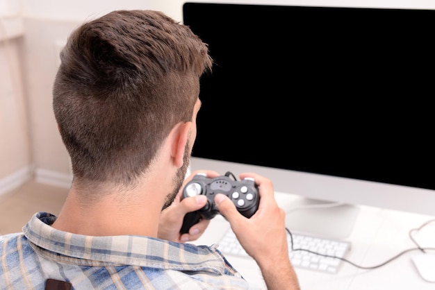 家でコンピューターゲームをしている若い男