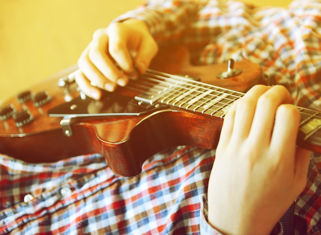 Young man playing electric guitar close up