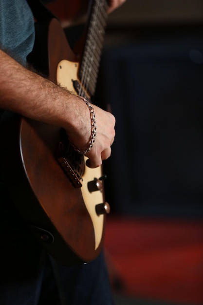 Young man playing on electric guitar close up