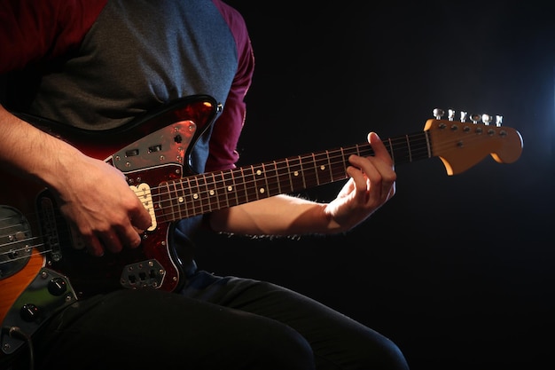 어두운 배경에서 일렉트릭 기타를 연주하는 젊은 남자