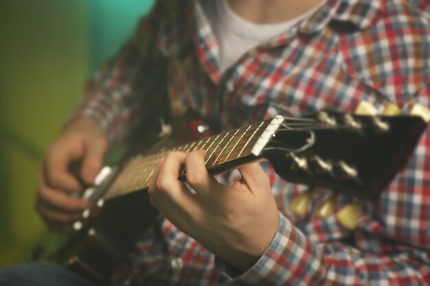 사진 조명 안개 배경에 전기 기타를 연주하는 젊은 남자