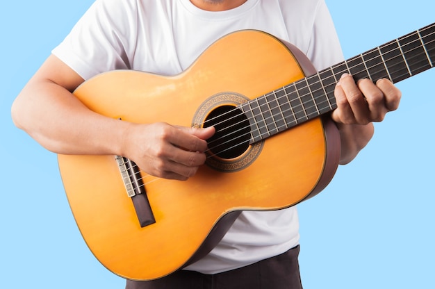 Young man playing guitar classic on blue background