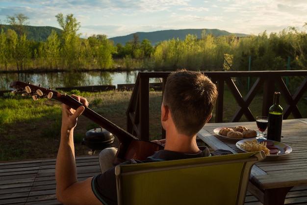 Foto giovane che suona la chitarra e che beve vino da solo