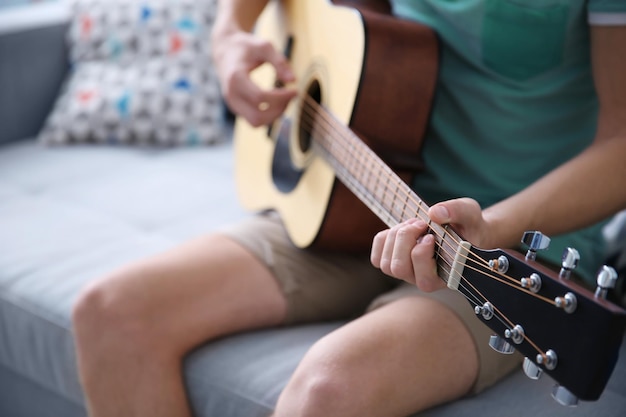 Young man playing guitar in a room