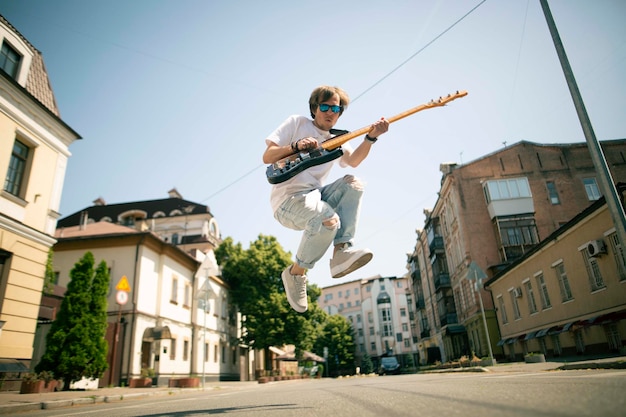 Giovane che suona la chitarra in una strada.