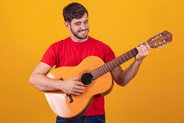 Young man playing guitar on yellow background with free space for text