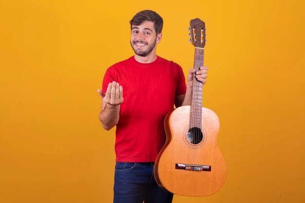 Young man playing guitar on yellow background with free space for text