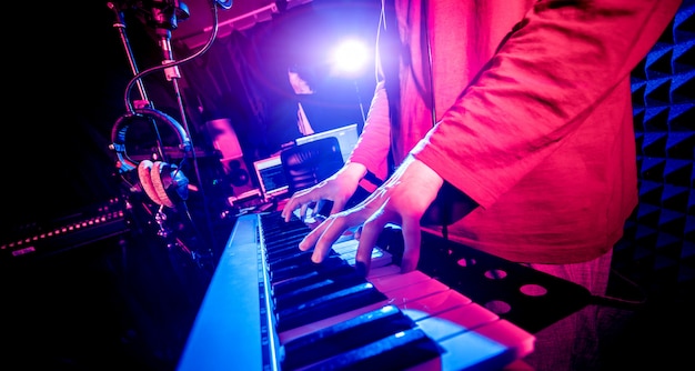 Young man playing piano in sound recording studio.