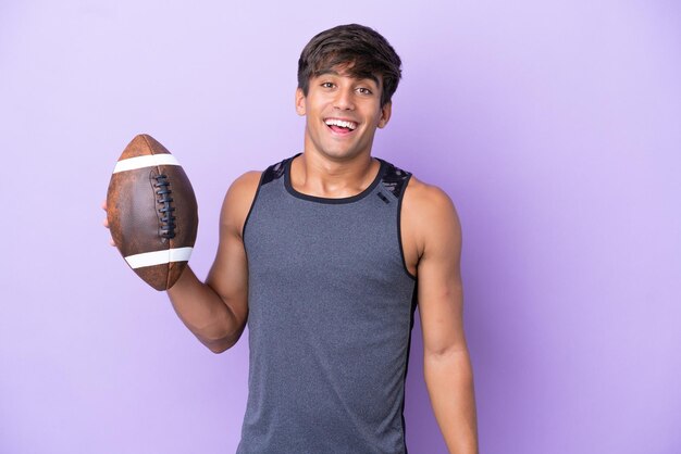 Young man playing rugby isolated on purple background with\
surprise facial expression