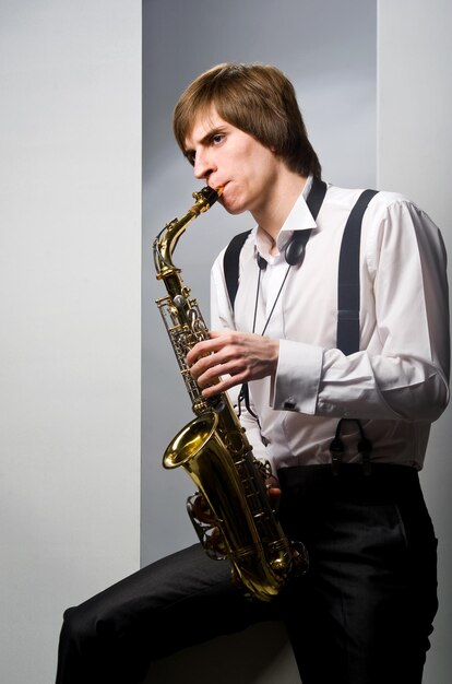 Young man playing the saxophone over white background