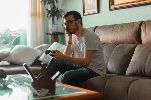 Young man playing video game holding wireless controller