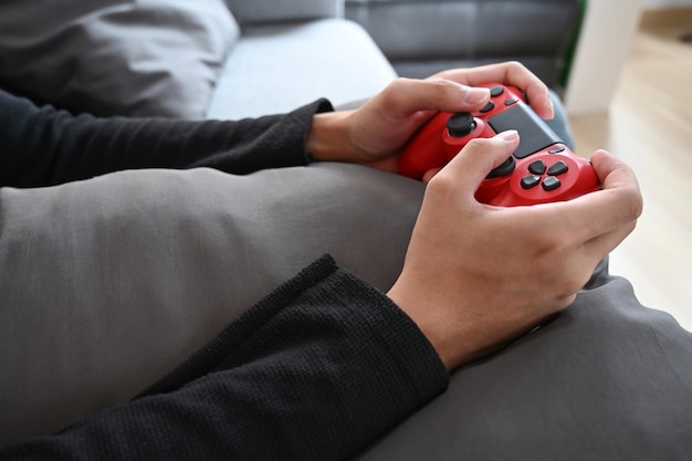 Photo young man playing video game with joystick while sitting on couch