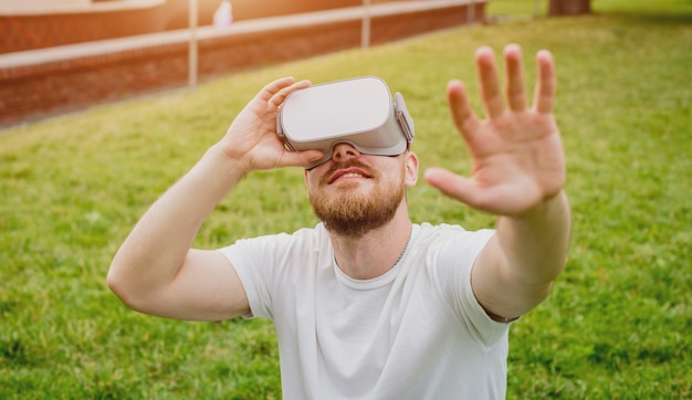 A young man plays a game wearing virtual reality glasses on the street.