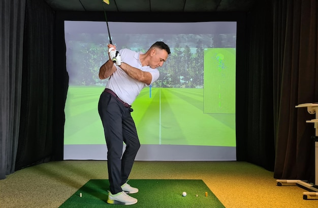 Photo young man plays golf indoors golf simulator