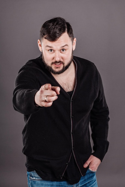 Young man pointing with his finger against a grey background