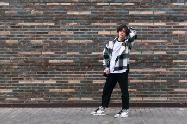 Young man posing against a brick wall