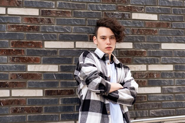 Young man posing against a brick wall