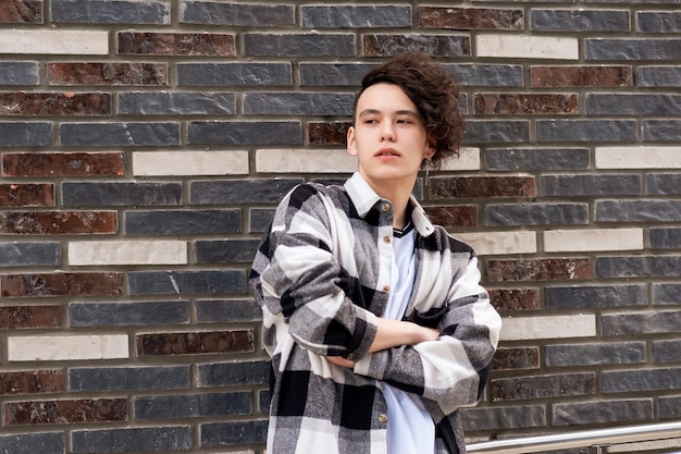 Young man posing against a brick wall