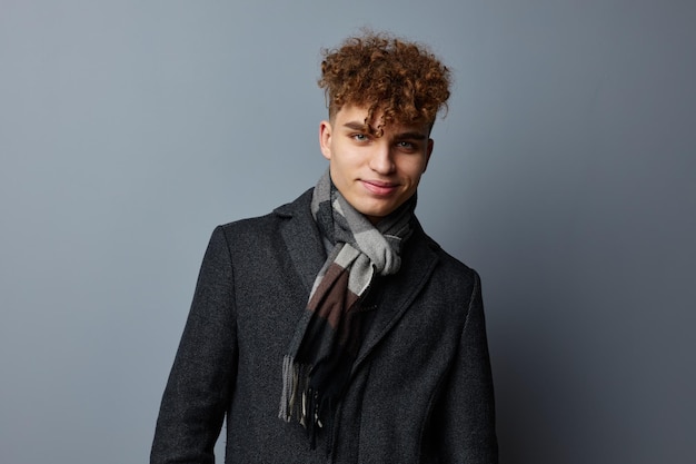 Young man posing on gray background in coat