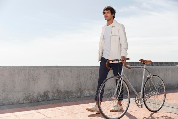 Photo young man posing next to his bike