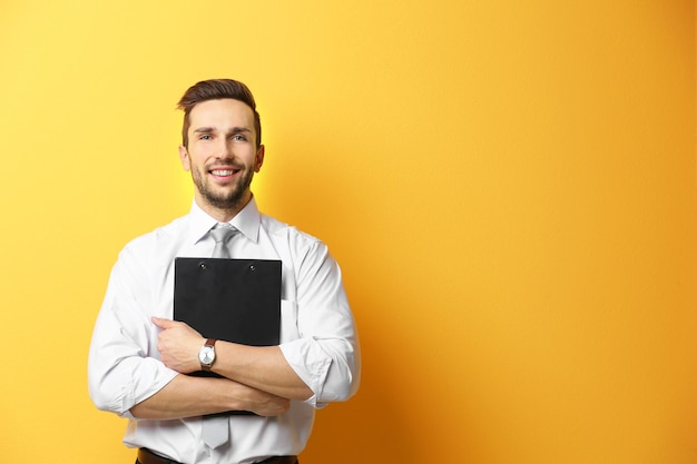 young man posing with clipboard on yellow