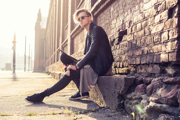 Young man posing with a trendy outfit against a urban background