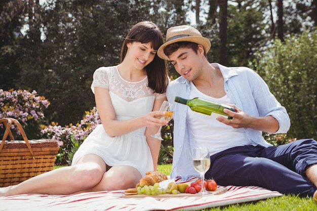 Young man pours to woman wine in a glass during a picnic