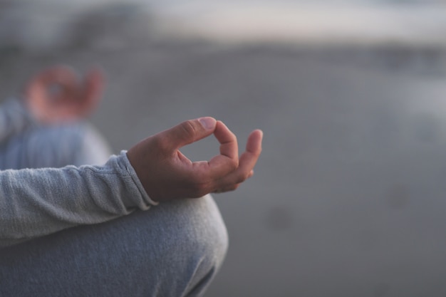 Giovane pratica yoga sulla spiaggia al tramonto.