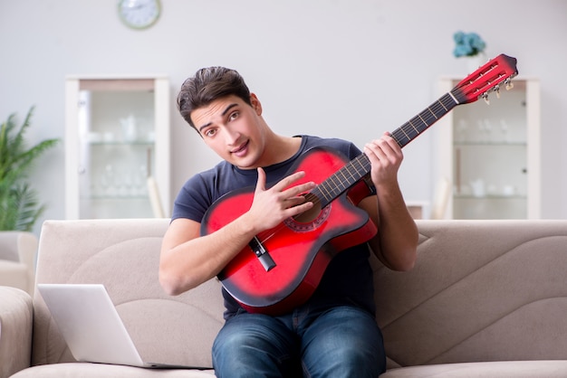 若い男が自宅でギターを弾く練習