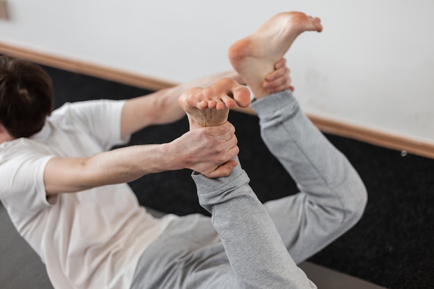 Young man practicing yoga in the gym. Guy in sportswear is stretching his back.