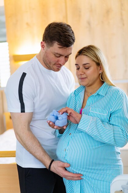Foto un giovane uomo e una donna incinta sono in piedi nella stanza e tengono il bambino tra le mani