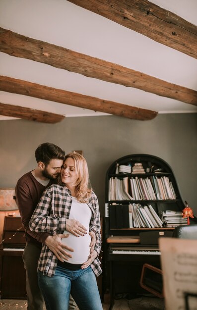 Young man and pregnant woman hugging in the room at home