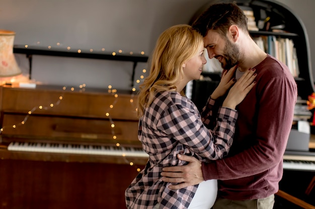 Young man and pregnant woman hugging in the room