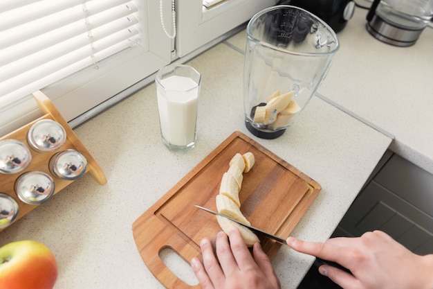 A young man prepares a smoothie of milk and fresh fruit for breakfast.