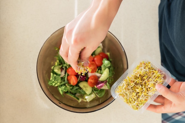 Young man prepares a very healthy salad of fresh organic vegetables and herbs