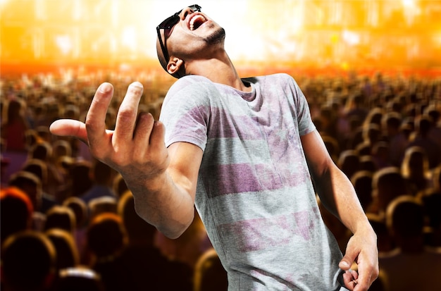 Young man pretending playing on guitar on blurred concert background