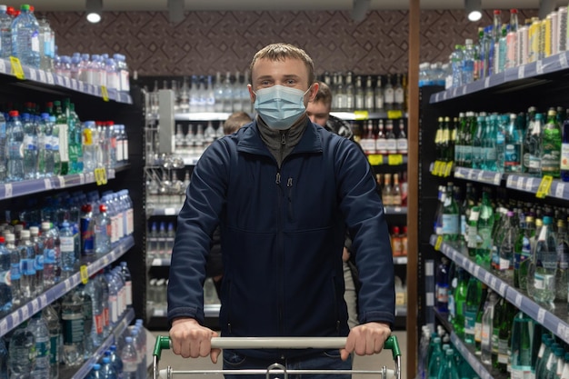 A young man in a protective face mask in a supermarket Food and drinks Pandemic