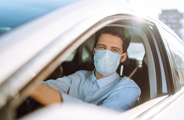 Young man in a protective mask sitting in the car